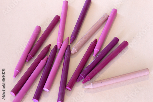 This is a photograph of Pink and Purple crayons on a colorful craft paper background