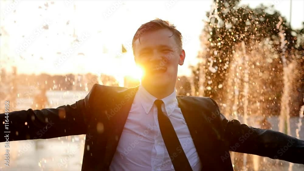 happy young business man dancing in the rain outdoors at sunset. slow motion