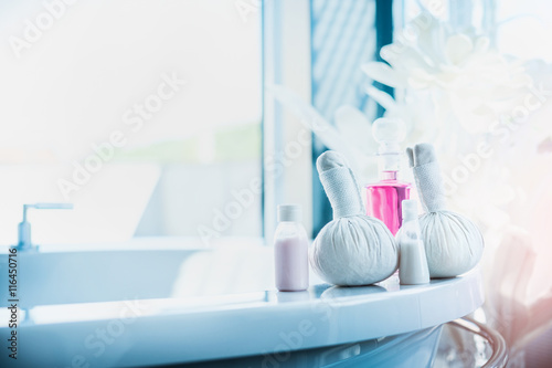Herbal compress stamps   pink lotion bottle on light luxury bath at window. Spa or wellness background