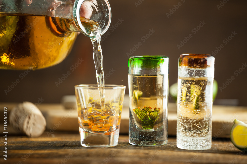 Pouring Tequila into shot glass. Selective focus. Blurred background. - obrazy, fototapety, plakaty 