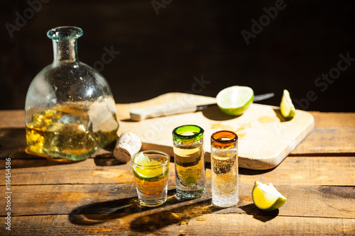 Shot glass of tequila on wood table. Selective focus. Blurred background.