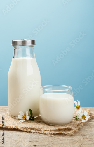 A bottle of rustic milk and glass of milk on a wooden table on a
