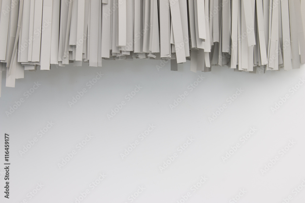 Paper shredded on white background. Paper shredder hang on white wall.  Shredded documents on wall. Stock Photo | Adobe Stock
