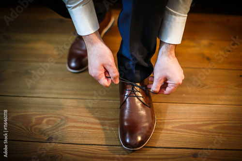 Handsome groom on his wedding day - tying a shoe lace