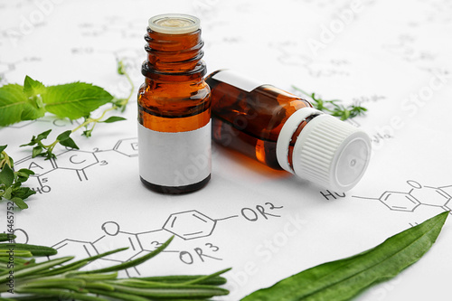 Dropper bottles and herbs on chemical formulas background