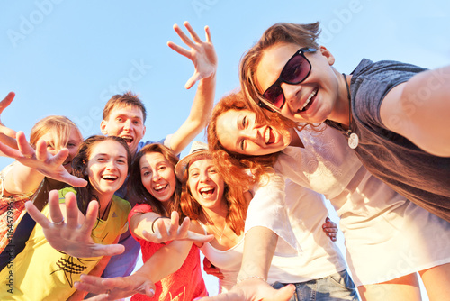 Group of happy young friends doing selfie against the blue sky. photo