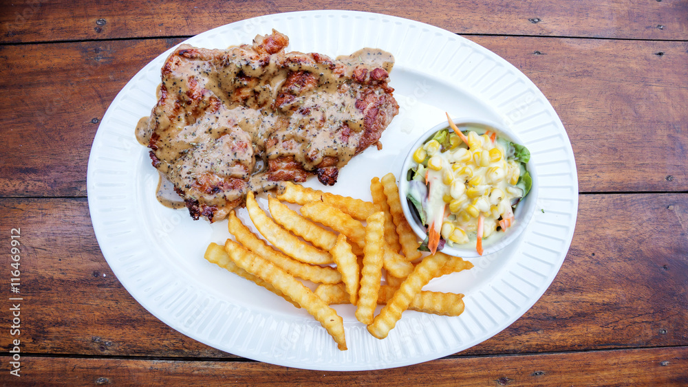 Grilled beef steak with french fries and corn salad.