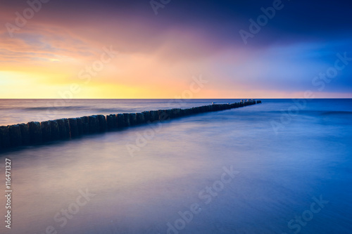 sunset on the beach with a wooden breakwater  long exposure