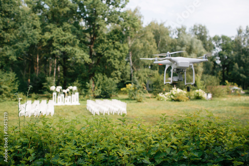 Videography wedding ceremony from the air a small spy quad copter scout drone flying through the trees in  forest.