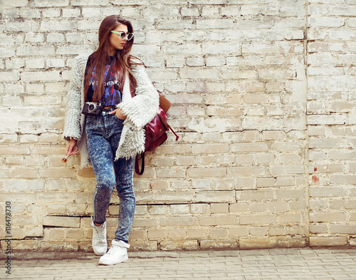 Young street fashion girl on the background of old brick wall. Outdoors, lifestyle.