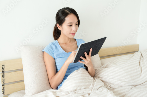 Asian woman using digital tablet on bed