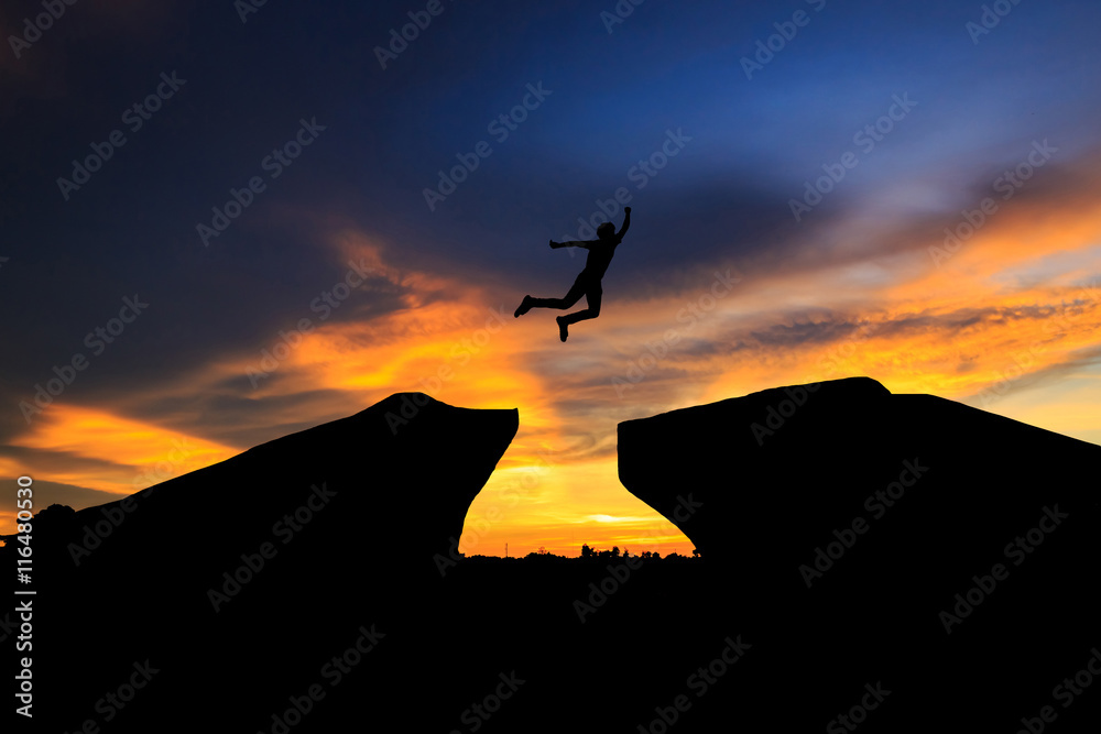 Man jump through the gap between hill.man jumping over cliff on sunset background,Business concept idea