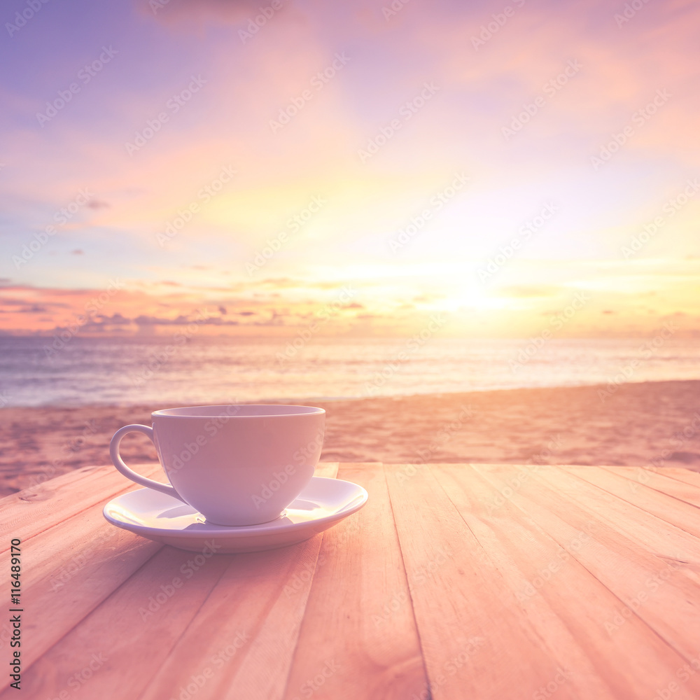 Coffee cup on wood table at sunset or sunrise beach with lens fl