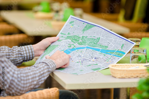 Caucasian young european man with citymap in outdoors cafe. Portrait of attractive young tourist on lunch time