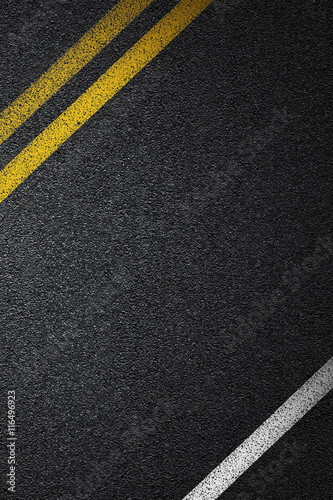 Level asphalted road with a dividing white and yellow stripes. The texture of the tarmac, top view.