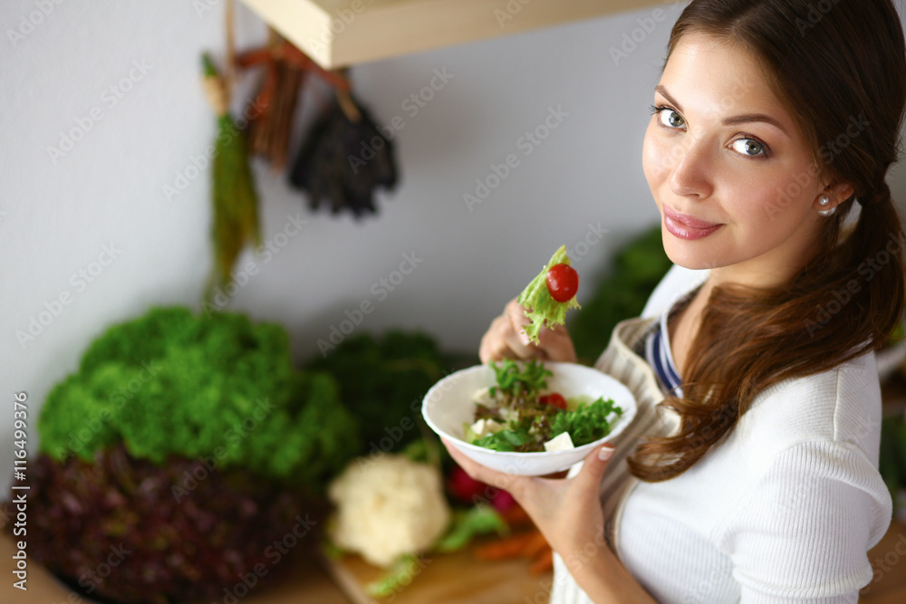 Young woman eating salad and holding a mixed salad Young woman eating salad and holding a mixed salad