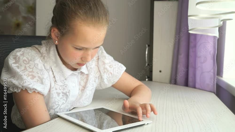Cute little girl uses a digital tablet computer Cute little girl uses a digital tablet computer