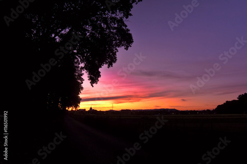 Evening scene with silhouettes of trees, houses, church, pylon and Ceske Stredohori mountains in village Brozany nad Ohri in bohemian landscape photo