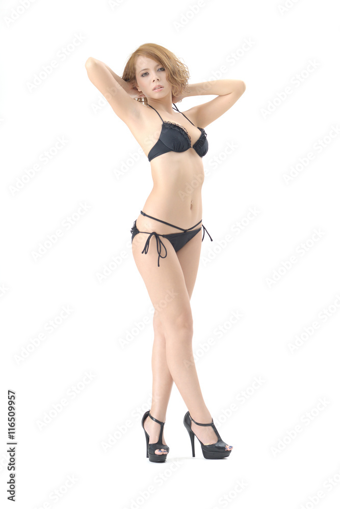 女性モデルが黒色のビキニの水着を着て立っています。スタジオで撮影された画像で、背景は白です。
