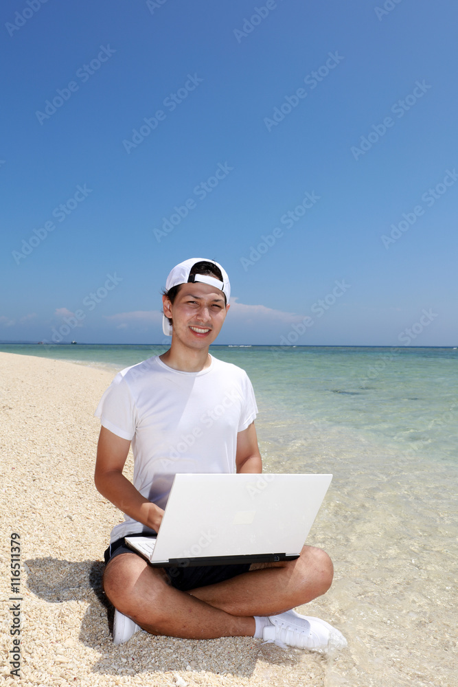 美しいビーチでパソコンを楽しむ笑顔の男性