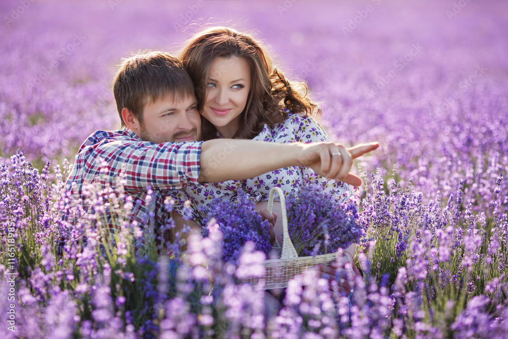 Young man and woman spend time in a lush field of lavender ,a pregnant woman,brunette with long curly hair holding a basket of flowers and the dark-haired man in a plaid shirt Young man and woman spend time in a lush field of lavender ,a pregnant woman,brunette with long curly hair holding a basket of flowers and the dark-haired man in a plaid shirt