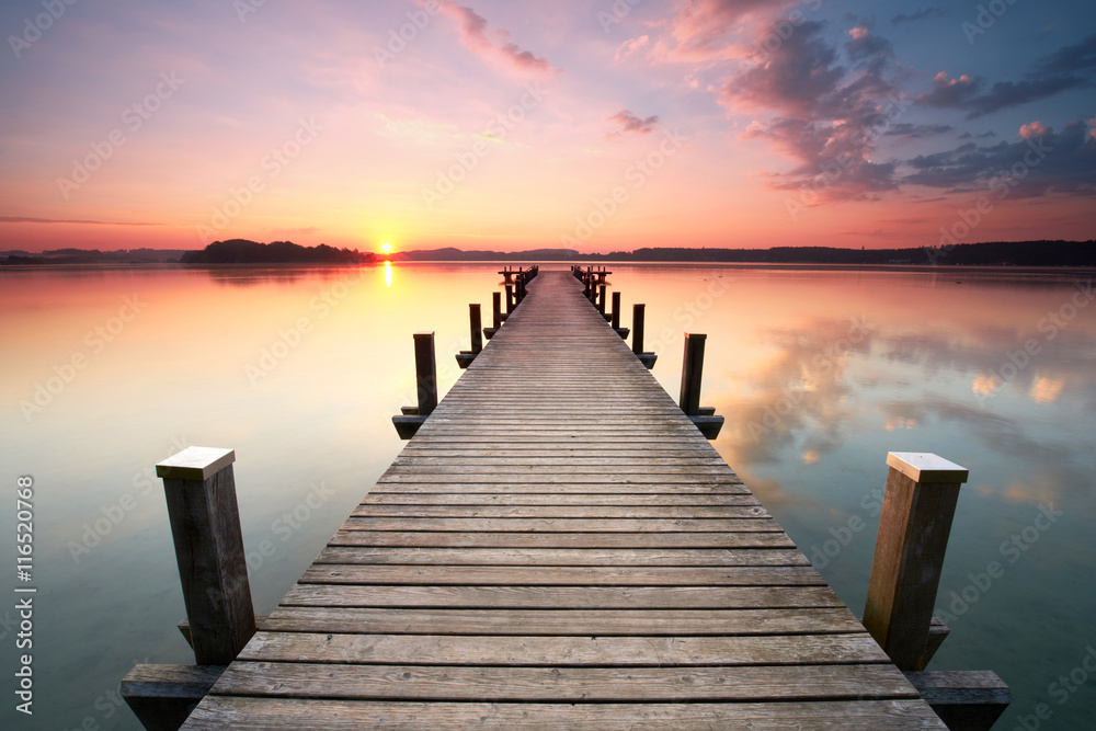 Fototapeta długa promenada na brzegu jeziora na wschód słońca w lecie