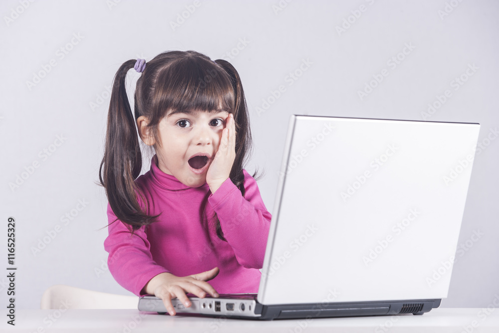 Cute little girl reacts with shock while using a laptop. Internet safety concept Cute little girl reacts with shock while using a laptop. Internet safety concept