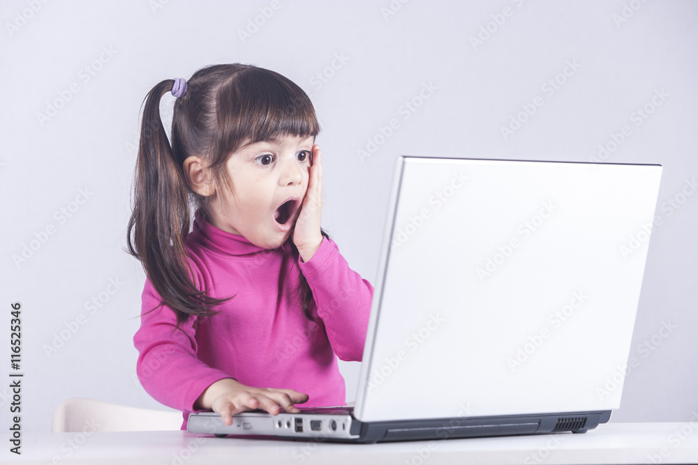 Cute little girl reacts with shock while using a laptop. Internet safety concept Cute little girl reacts with shock while using a laptop. Internet safety concept