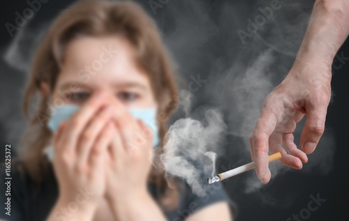 Passive smoking concept. Woman is covering her face from cigarette smoke.