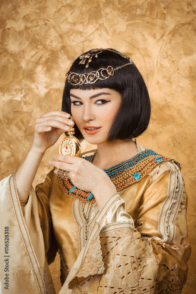 Beautiful Egyptian woman like Cleopatra with perfume bottle on golden ...
