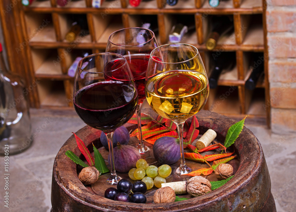 Red, rose and white glasses of wine. Grape, fig, nuts and leaves on old wooden barrel