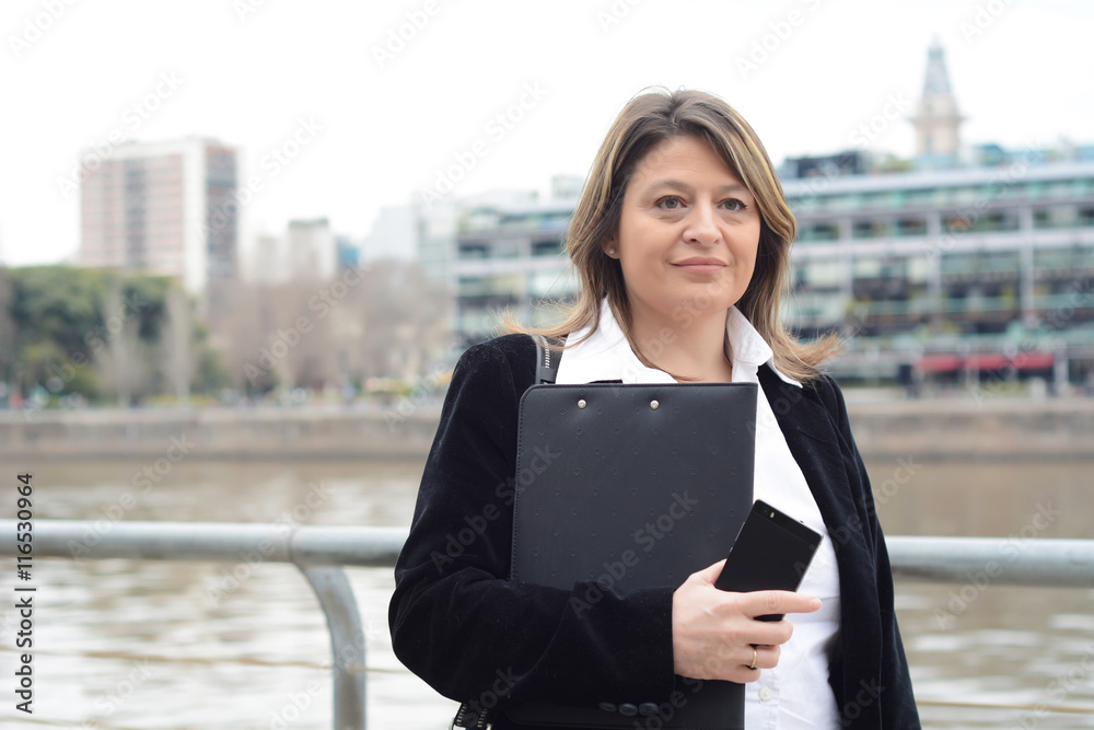 Fototapeta premium Portrait of business woman holding clipboard and smartphone.