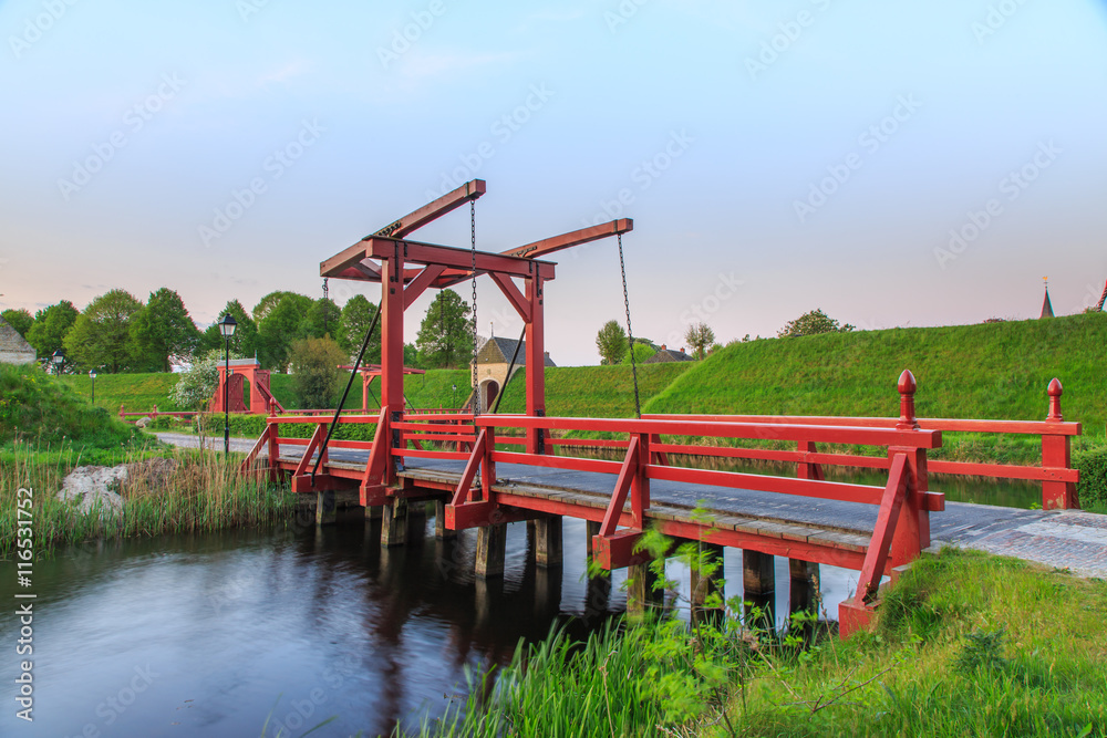 Close up of first access Jetty with drawbridge with in the background the city gate with access to the historic fortress town of Bourtange Close up of first access Jetty with drawbridge with in the background the city gate with access to the historic fortress town of Bourtange
