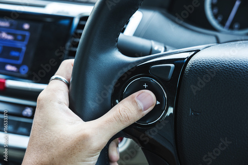 Asian man hand push button on steering wheel, selective focus on finger