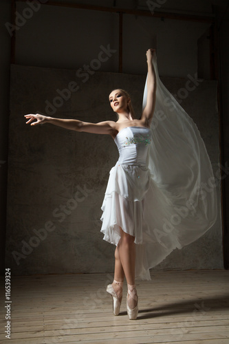 Elegant ballerina dancing in white costume and ballet shoes photo