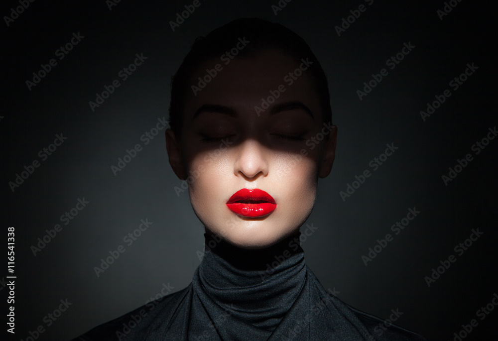 Beautiful model with bright red lips and face half covered in shadow ...