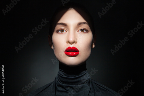 Attractive young model with red lips and forehead in shadow 