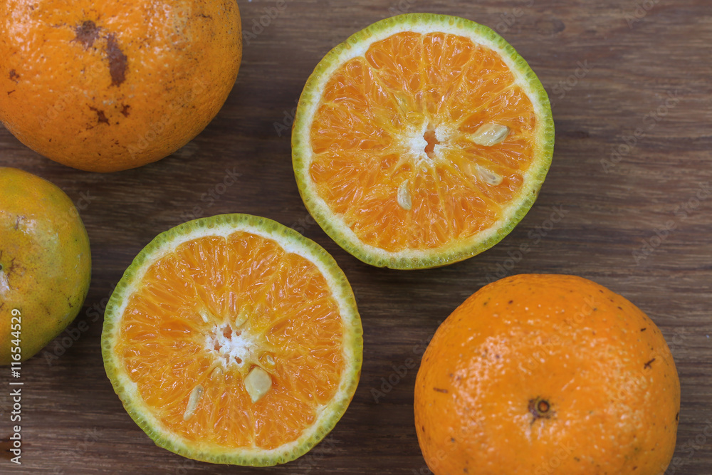 Orange, half of orange, orange lobule and basket with oranges on the wooden table Orange, half of orange, orange lobule and basket with oranges on the wooden table