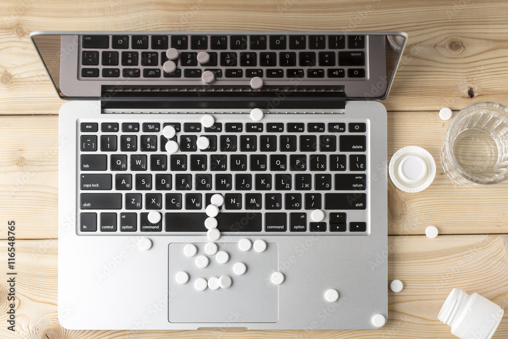 Heap of round white pills on the open laptop Heap of round white pills on the open laptop