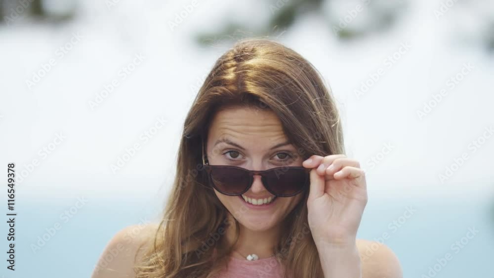 Young woman in sunglasses turns to camera and smiles Young woman in sunglasses turns to camera and smiles
