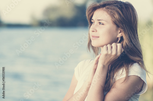 Vintage portrait of a tender young woman relaxed on the shore of the river at dawn