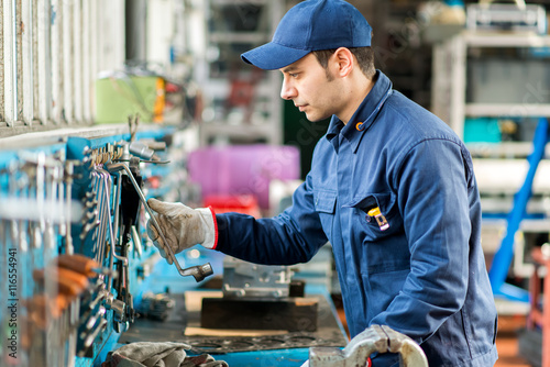 Принти на полотні Portrait of a worker searching for the right tool