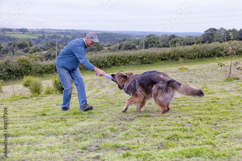 Man playing tug of war with his dog outside on the grass © Nicky Rhodes