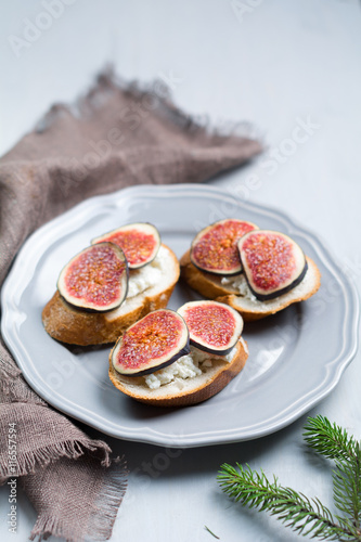 

Bruschetta with figs and goat cheese on a plate. Selective focus