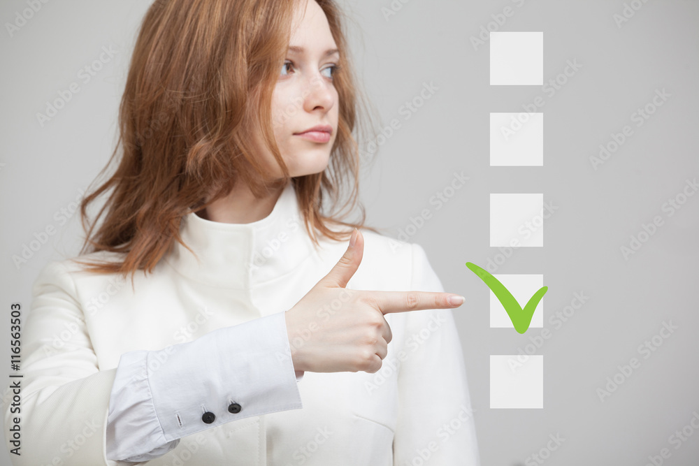 Young business woman checking on checklist box. Gray background. Young business woman checking on checklist box. Gray background.