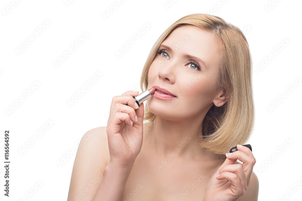 Beautiful middle aged woman applying lipstick