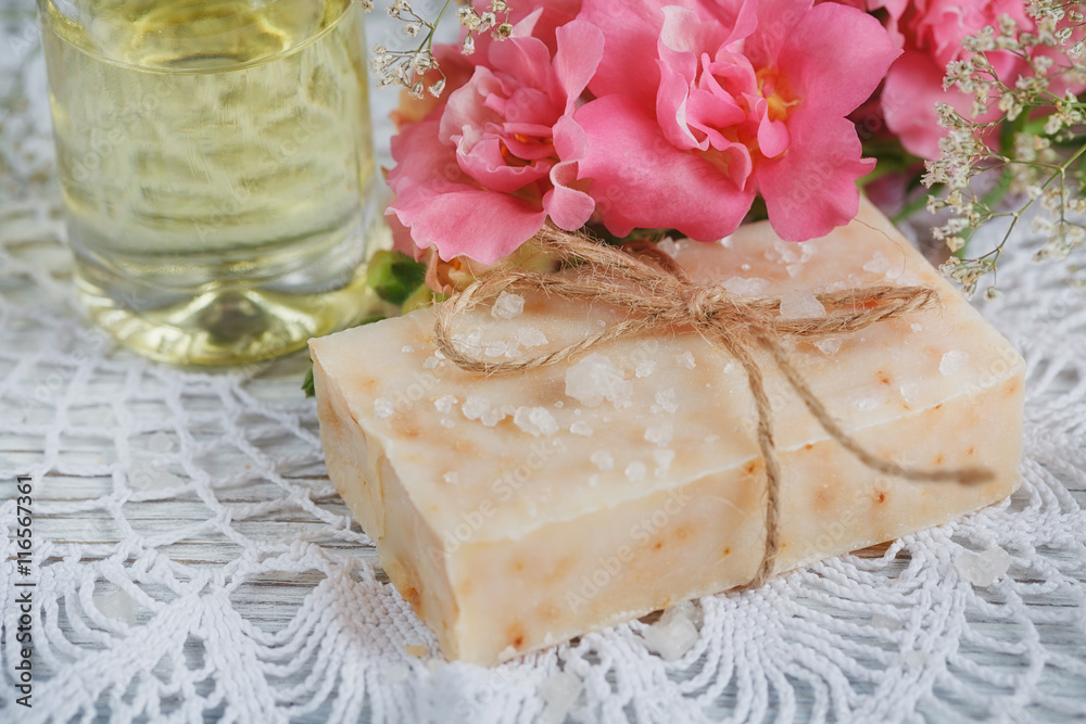 Natural handmade soap, aromatic oil and flowers on white wooden Natural handmade soap, aromatic oil and flowers on white wooden