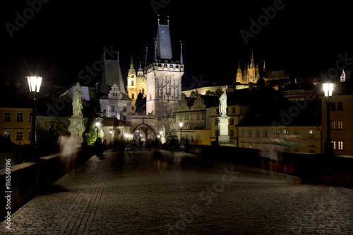 Colorful Prague gothic Castle with St. Nicholas' Cathedral and Bridge Tower from Charles Bridge above the River Vltava in the Night, Czech Republic