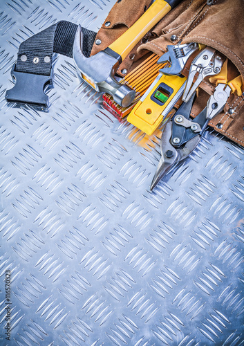 Set of construction tooling in toolbelt on channeled metal backg