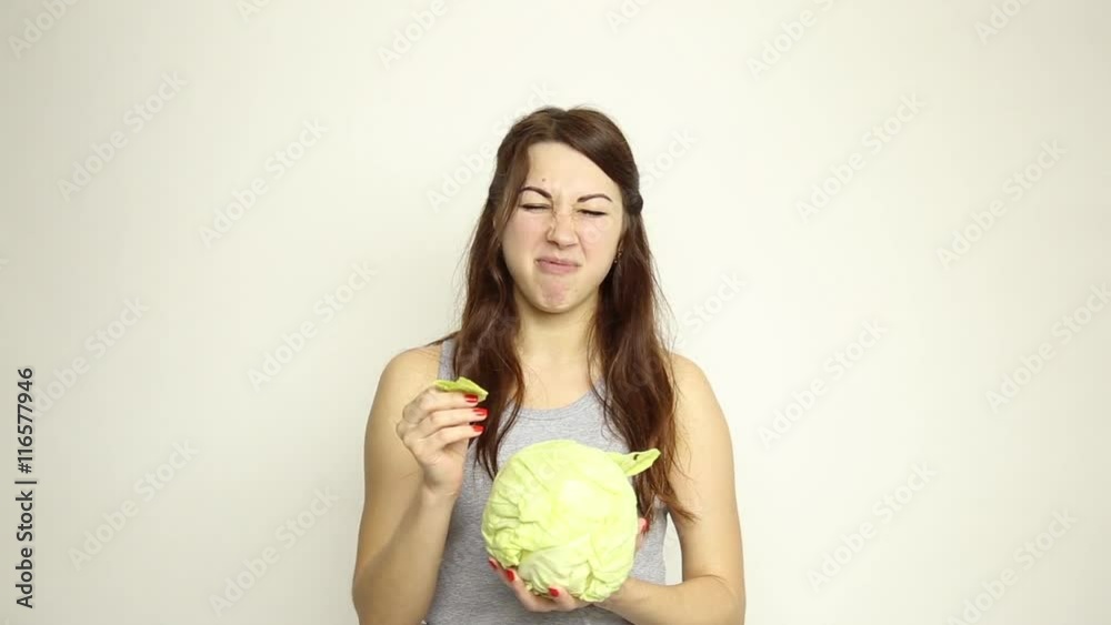 beautiful young woman eating an vegetables. holding cabbage, she stares at the head of cabbage. healthy food - healthy body concept beautiful young woman eating an vegetables. holding cabbage, she stares at the head of cabbage. healthy food - healthy body concept